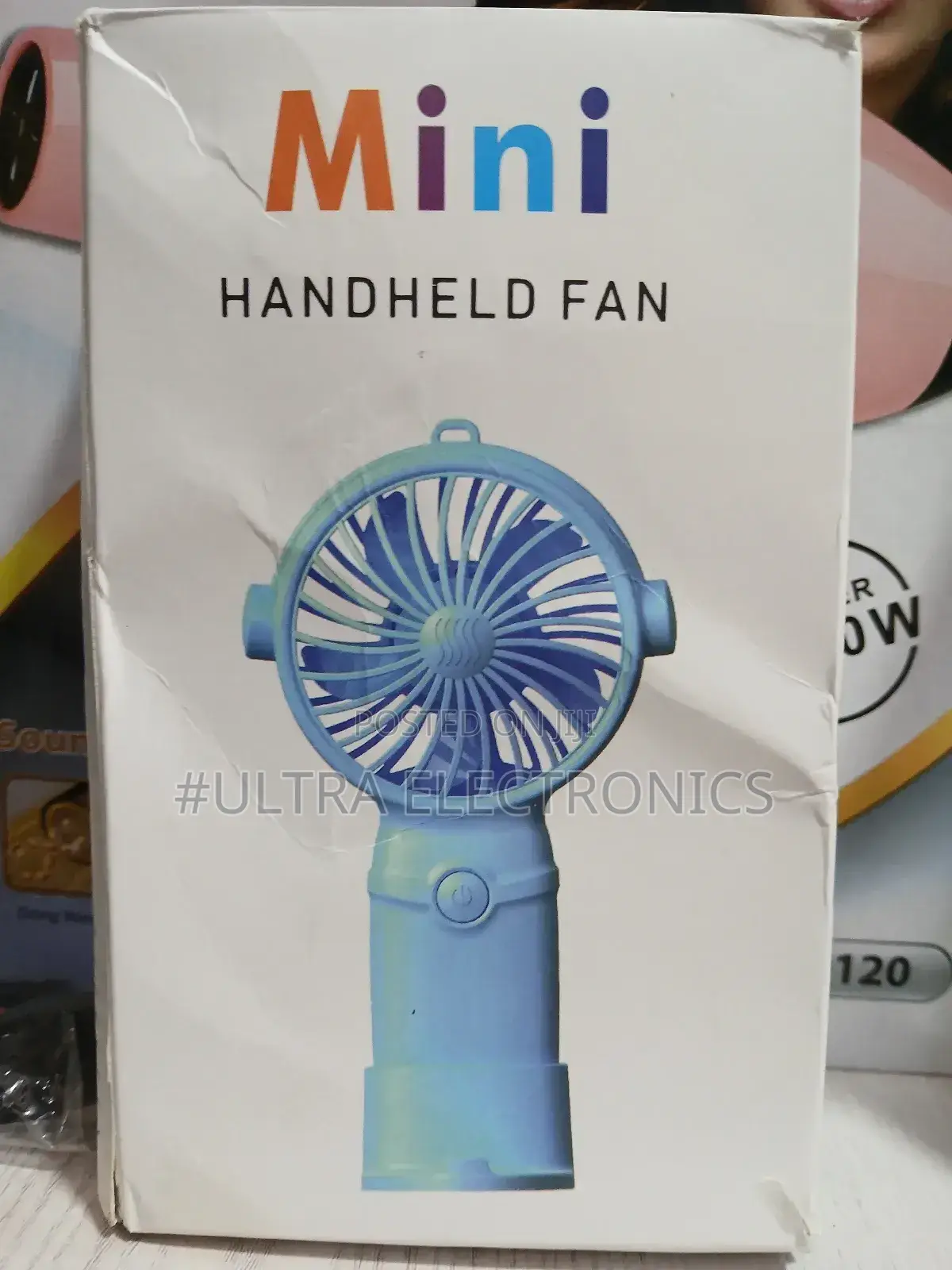 Mini Handheld Fan Packaged in Its Product Box. T